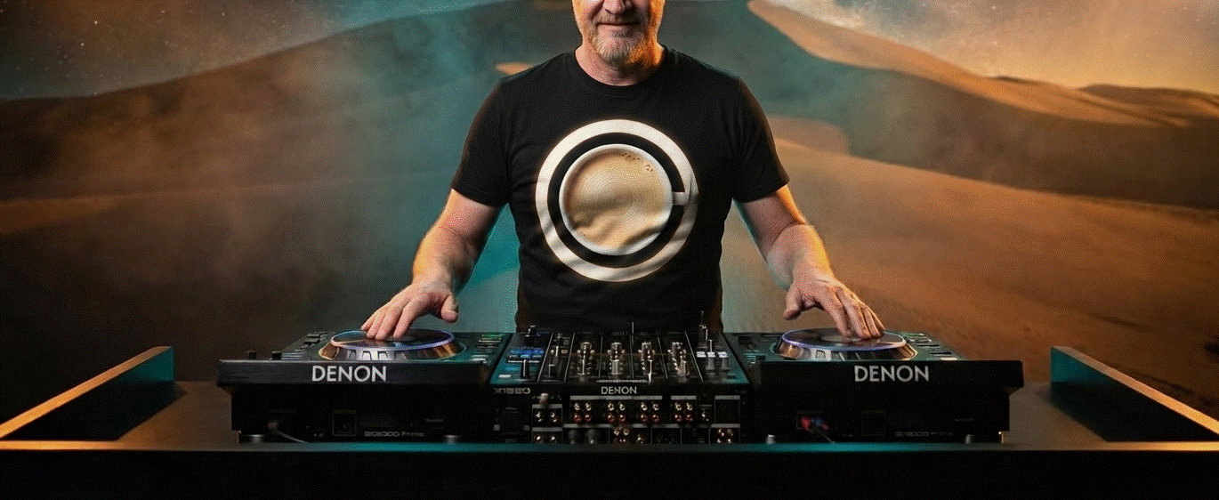 WitKoffie behind Denon DJ decks wearing the WitKoffie logo t-shirt, desert dunes backdrop